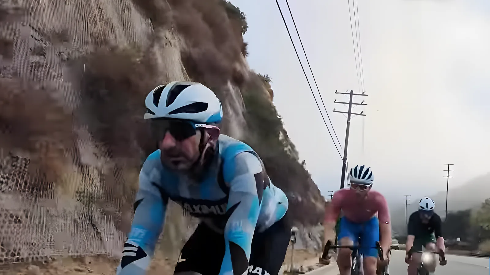 Bus Stop rider in a light blue long-sleeve jersey beside a rocky hillside