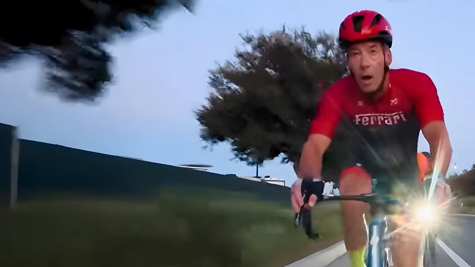 Coffee Crew rider in a red jersey with a front light on, riding at dawn