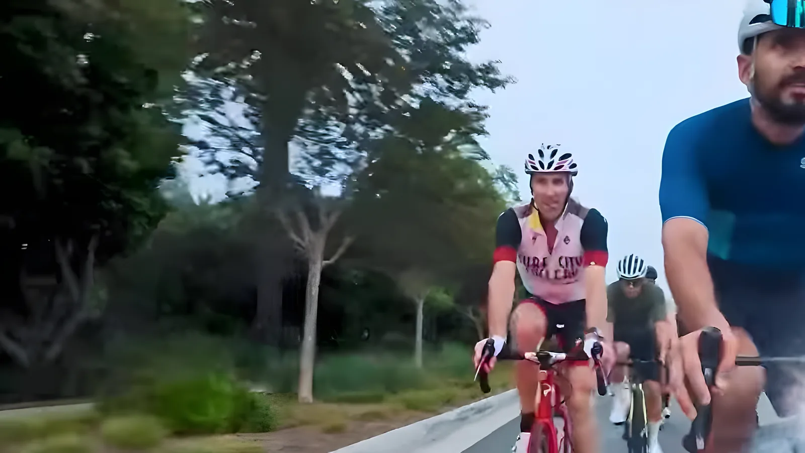 Two Coffee Crew riders side by side on a tree-lined road